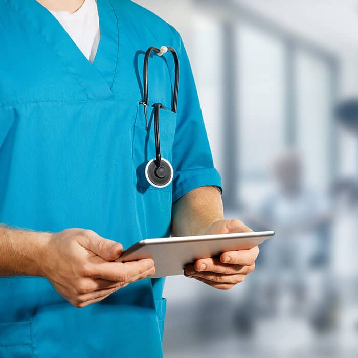 Medical professional holding tablet with stethiscope in pocket