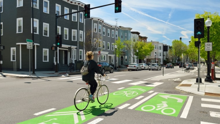 woman riding bike across cross walk