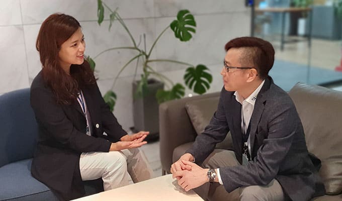 Two young adults talking at a table sitting on couches