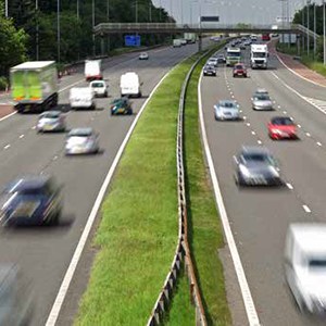 Three lane highway in both directions with cars traveling in high speed