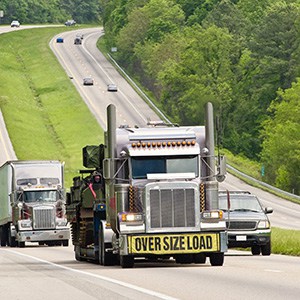 Truck on highway with sign on front bumper that says over size load