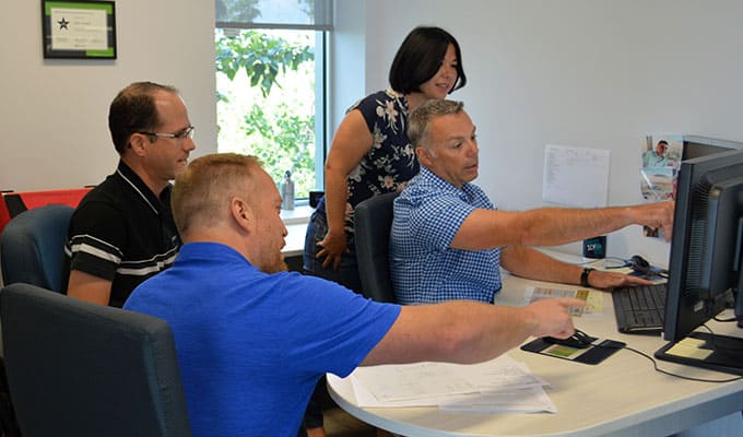 diverse group of coworkers talking about a project pointing to the computer screen