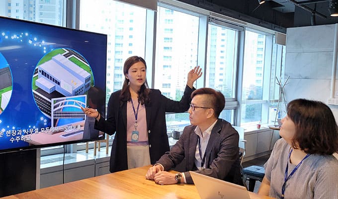 woman presenting a project to the group while displaying supporting graphics on the screen