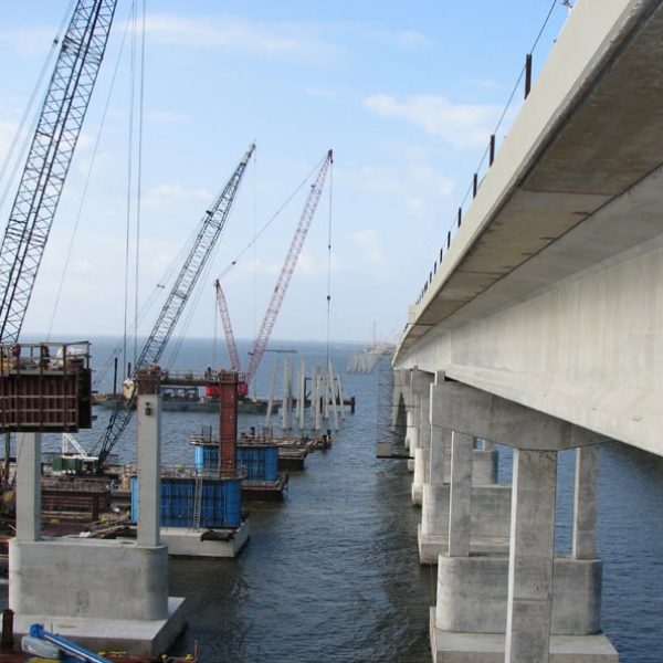 Construction in progress on a concrete bridge over a water mass