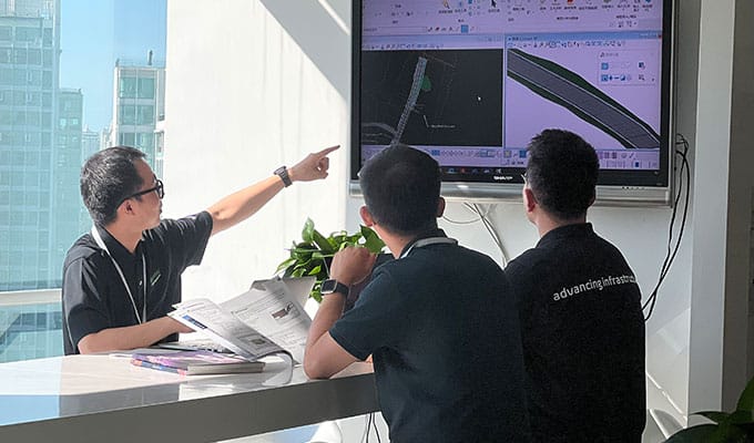 group of coworkers sitting around a display point to the screen discussing the project