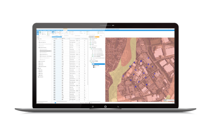 A laptop screen displays a geographic information system (GIS) map interface with marked locations alongside a detailed data table.
