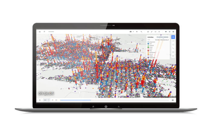 A laptop screen displays a 3D data visualization map with numerous vertical bars of varying heights and colors representing data points overlaid on a geographic location.
