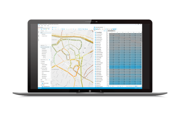 A laptop screen displaying a geographic information system (GIS) software interface, showing a detailed map on the left and a data table on the right.