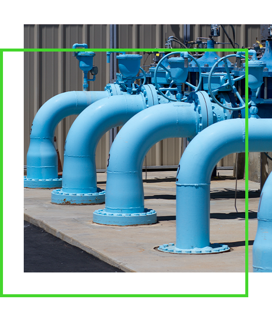 a square image of multiple large blue water line pipes that are above ground and are going into the ground, along with green overlapping border that lays on top of the image | Bentley Systems | Infrastructure Engineering Software Company a square image of multiple large blue water line pipes that are above ground and are going into the ground, along with green overlapping border that lays on top of the image