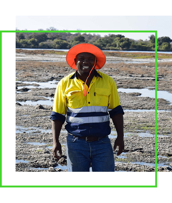 A man in an orange hat standing in a muddy area. | Bentley Systems | Infrastructure Engineering Software Company A man in an orange hat standing in a muddy area.