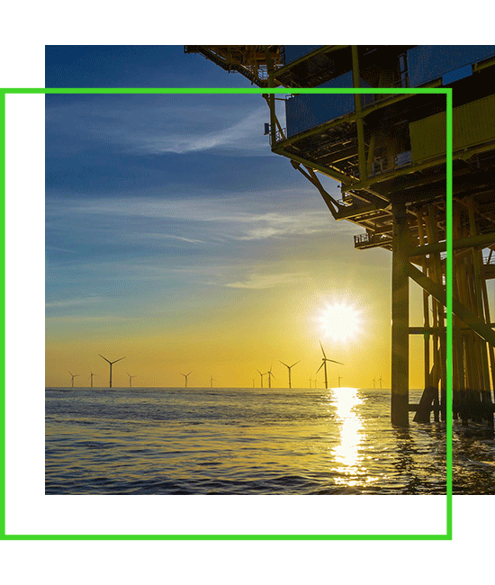 An oil rig with wind turbines in the background. | Bentley Systems | Infrastructure Engineering Software Company An oil rig with wind turbines in the background.